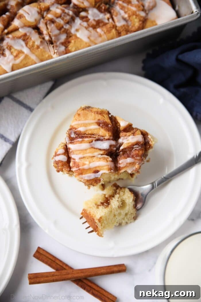 Fork full of cinnamon roll cake ready to be eaten.