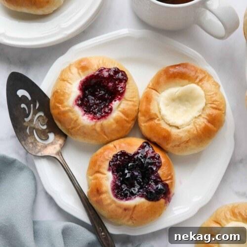 Raspberry, blueberry, and cream cheese kolaches on a plate.