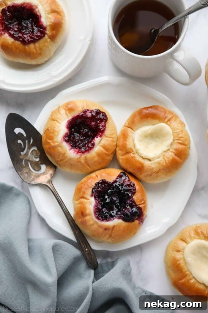 Raspberry, blueberry, and cream cheese kolaches on a plate.