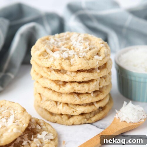 A stack of soft and chewy coconut cookies with extra shredded coconut on top.