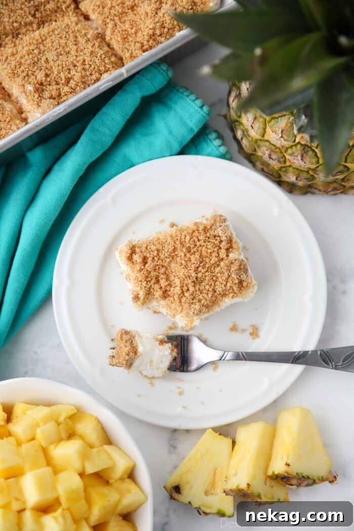 Top view of a rectangular slice of pineapple delight on a plate with a fork-full taken out.