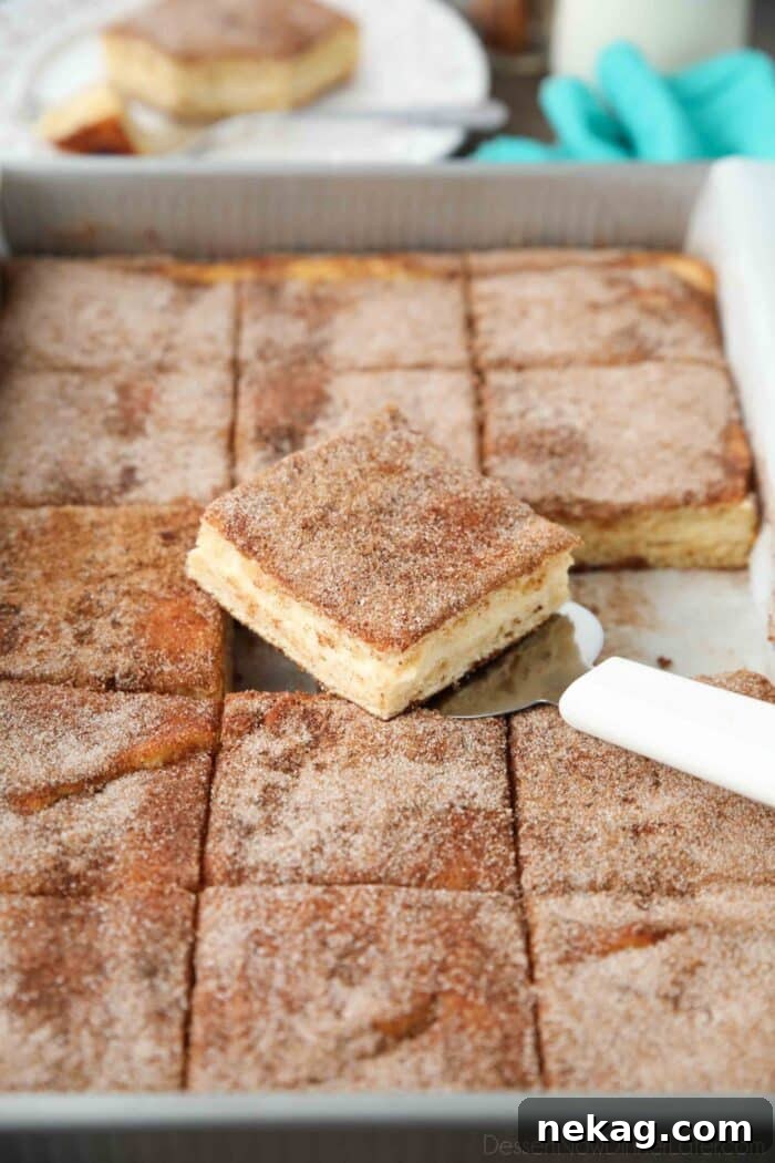 Spatula removing a piece of sopapilla cheesecake bars from a pan.