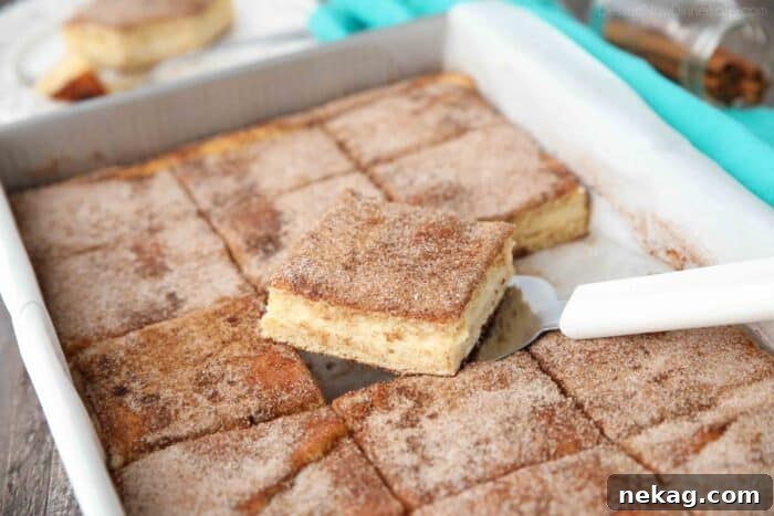 Spatula removing a piece of churro cheesecake bars from a pan.
