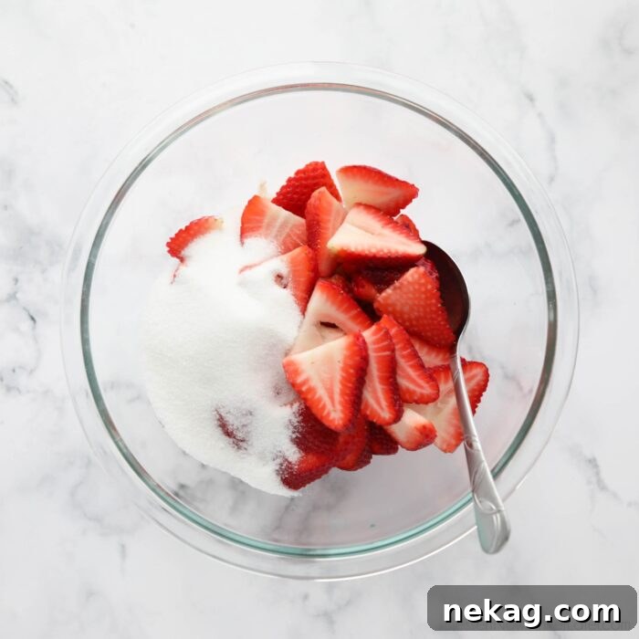 Flaky Biscuit Strawberry Shortcake Recipe You’ll Love 5 Sugar and sliced strawberries in a bowl.