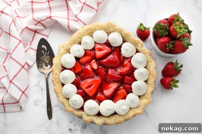 Top view of fresh strawberry pie with jello glaze and whipped cream.