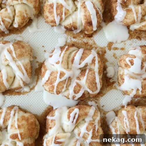 Icing drizzled over baked cinnamon roll knots.