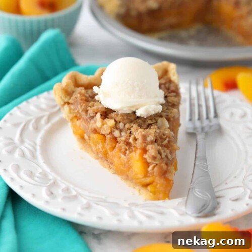 Slice of peach crumb pie on a plate with vanilla ice cream on top.