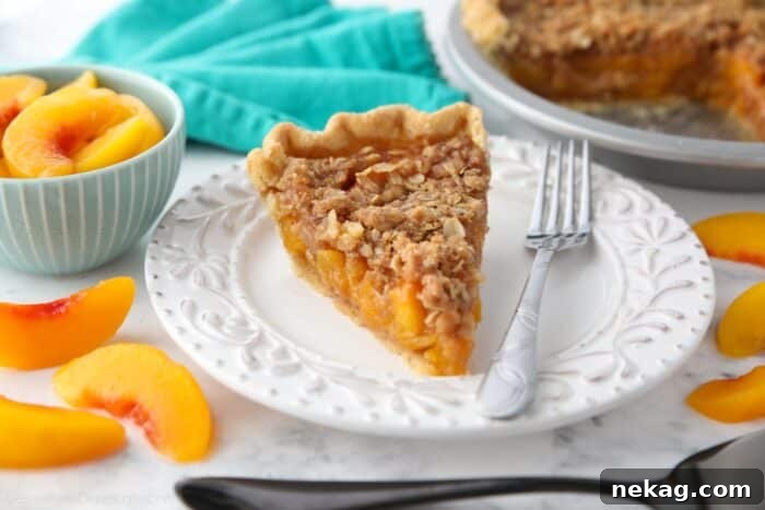 Slice of peach crumble pie on a plate with a fork.