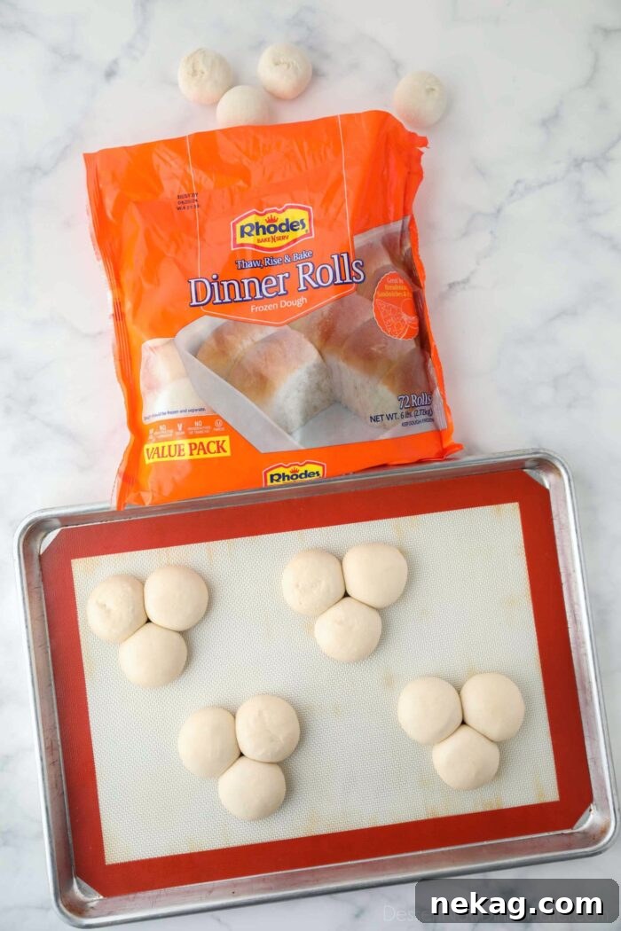 Package of Rhodes rolls with four groups of three rolls close-together; thawed on a sheet pan.