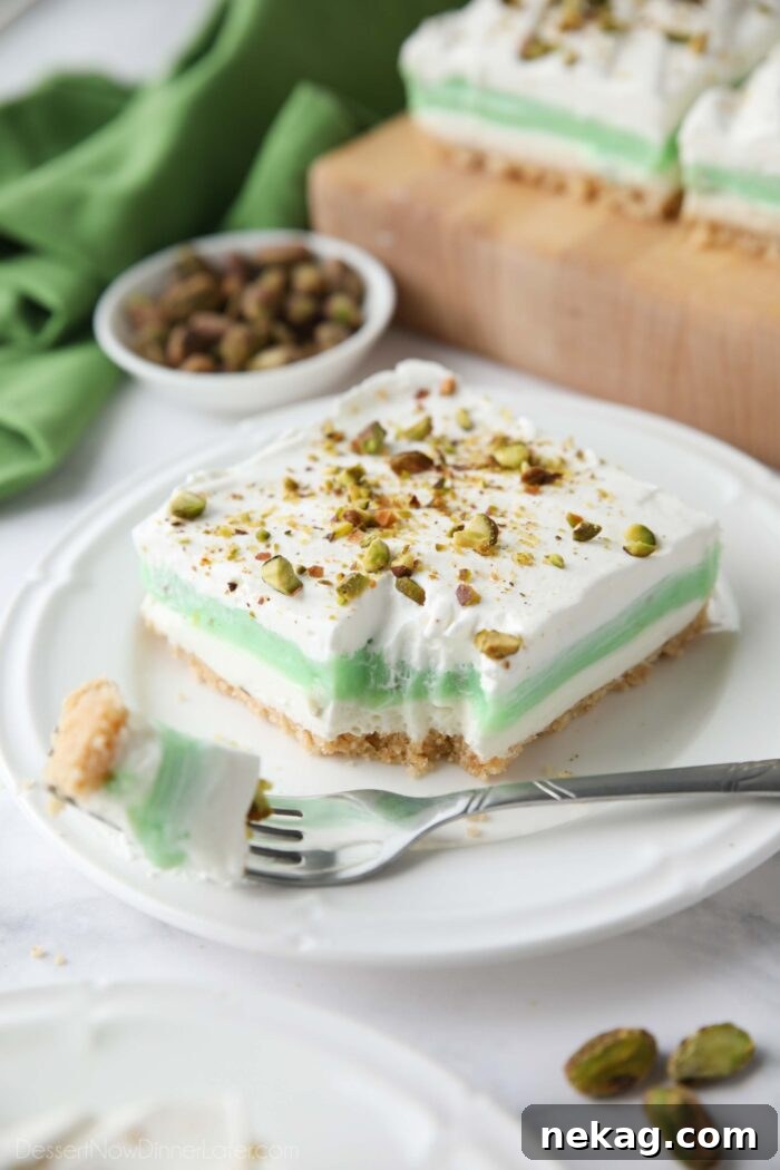 Decadent Pistachio Dessert Recipes to Impress Guests 2 Layered pistachio dessert on a plate with a fork-full taken out.