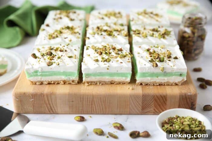 Decadent Pistachio Dessert Recipes to Impress Guests 12 Side view of squares of layered pistachio dessert on a cutting board.
