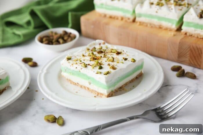 Decadent Pistachio Dessert Recipes to Impress Guests 13 Layered dessert with a shortbread cookie crust, no-bake cheesecake layer, pistachio pudding layer, and whipped cream on top sprinkled with chopped pistachios.