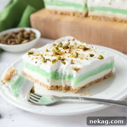 Decadent Pistachio Dessert Recipes to Impress Guests 14 Layered pistachio dessert on a plate with a fork-full taken out.