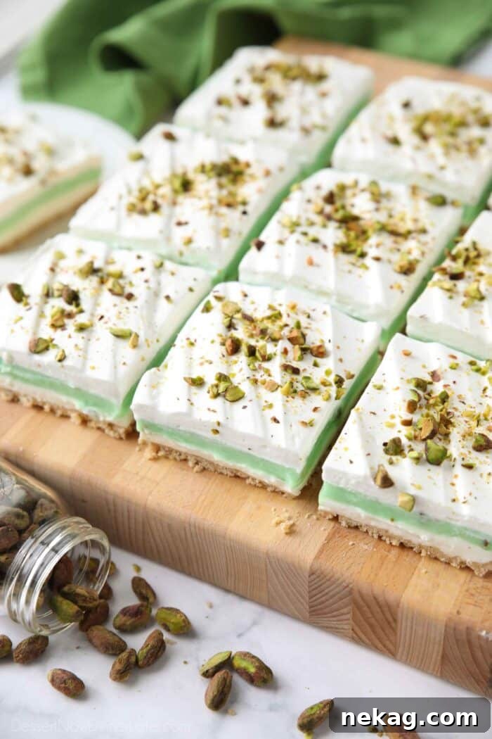 Decadent Pistachio Dessert Recipes to Impress Guests 3 Side view of squares of layered pistachio dessert on a cutting board.