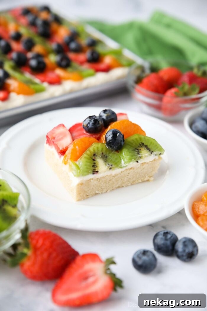 Square of sugar cookie fruit pizza on a plate.