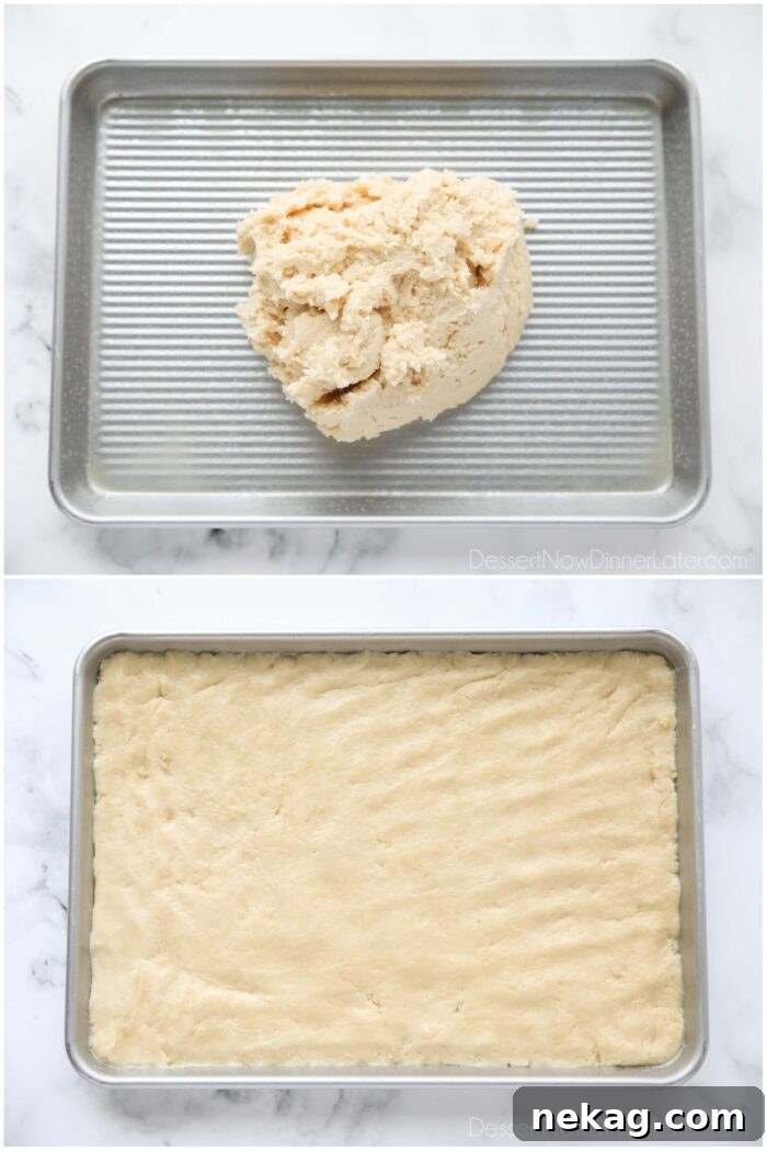 Sugar cookie dough being pressed into a 1/4 sheet pan (aka 9x13 pan).