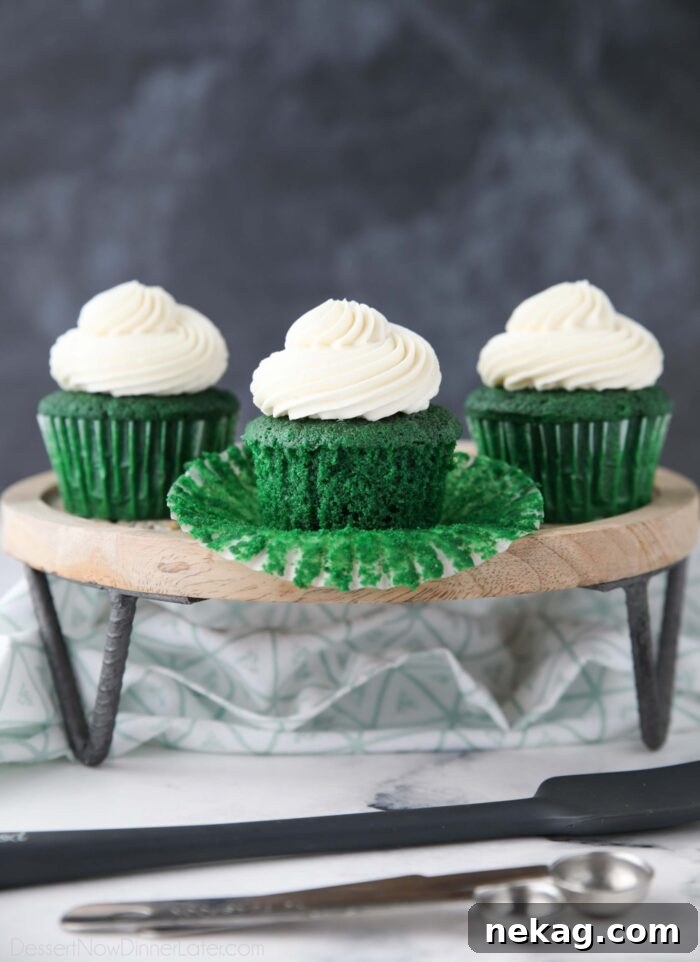Green velvet cupcakes on a cake stand. One with the wrapper pulled down.