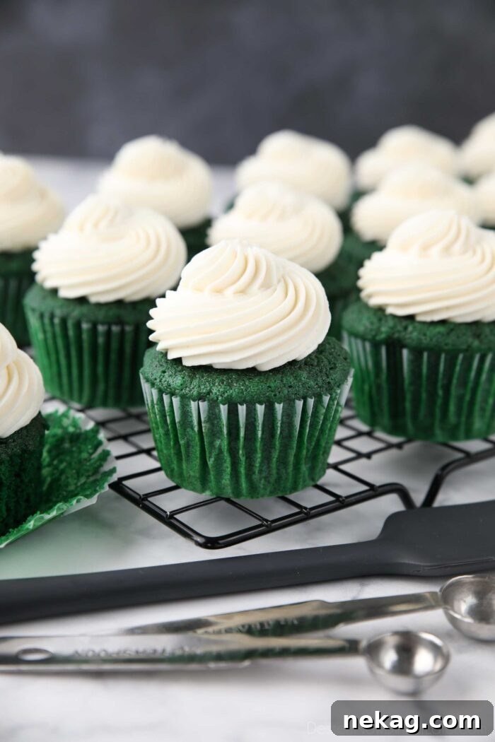 Close up of green velvet cupcakes with whipped cream cheese frosting piped on top.