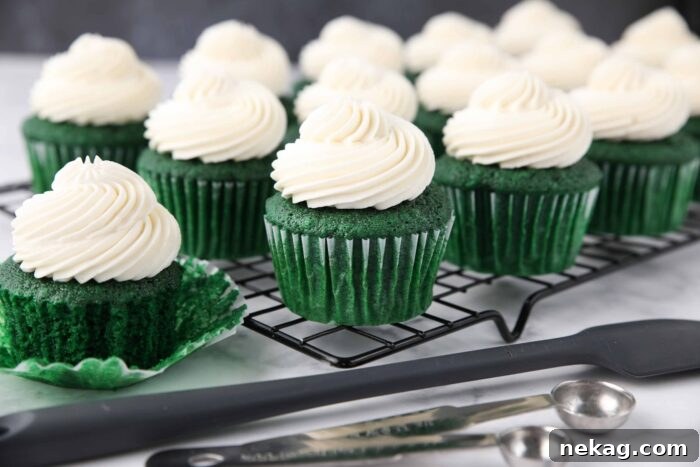 Close up of green velvet cupcakes with whipped cream cheese frosting piped on top.