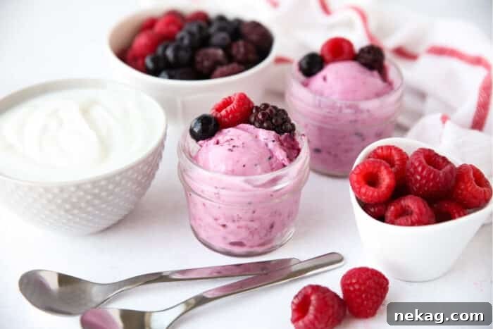 Berry frozen yogurt served inside of small mason jars with fresh berries.