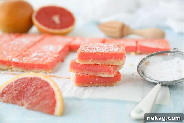 Grapefruit bars (like lemon bars) stacked on top of each other with a dusting of powdered sugar.