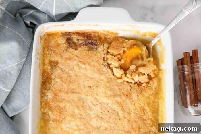 Top view of peach dump cake in pan being scooped with a spoon.