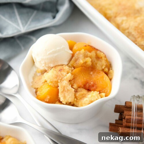 Peach dump cake (aka peach cobbler with cake mix) in a bowl with a scoop of vanilla ice cream.