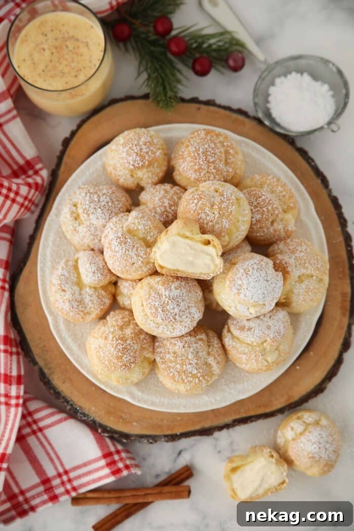 Top view of eggnog cream puffs with one cut open in the center.