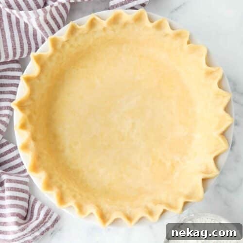 Top view of perfect pie crust in a pan with crimped edges.