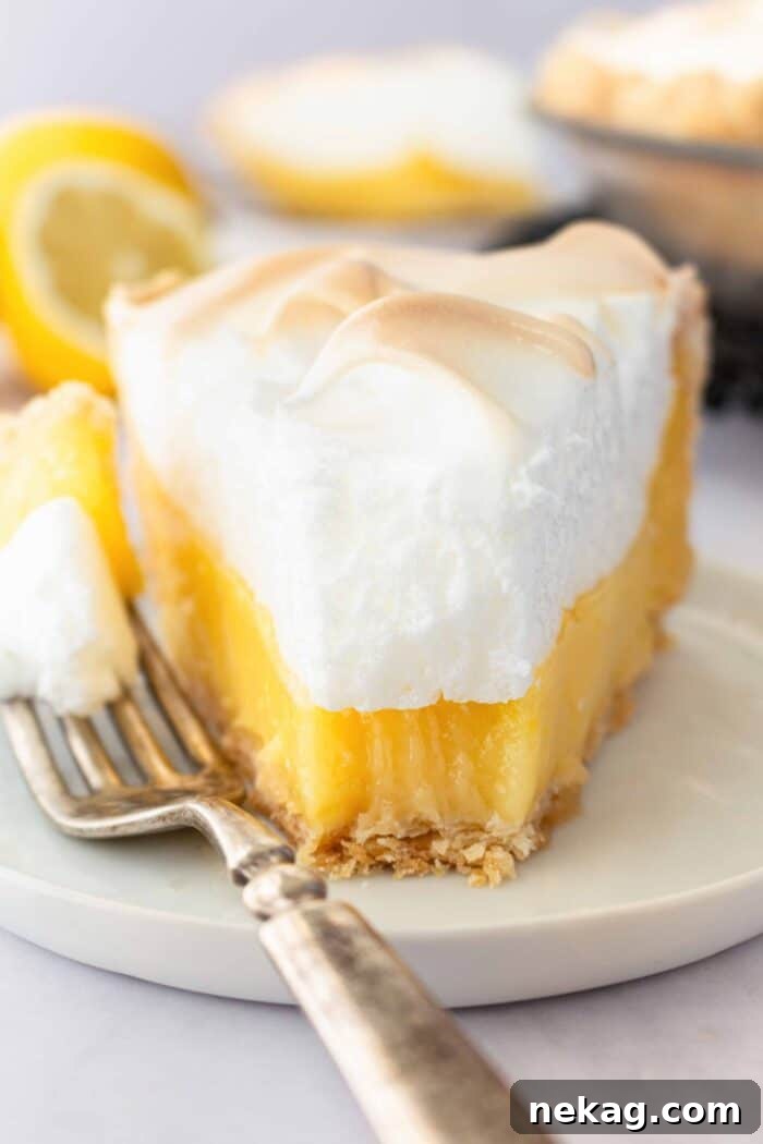 Classic Lemon Meringue Pie Recipe with Video Tutorial 2 Slice of lemon meringue pie on a plate with a forkful taken out.