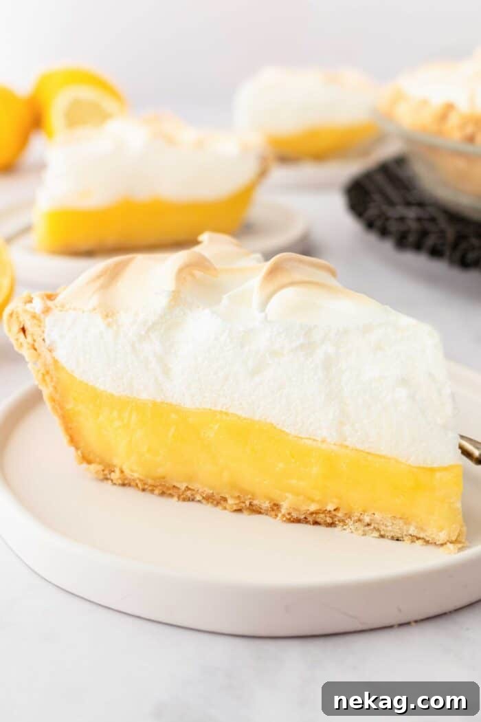 Classic Lemon Meringue Pie Recipe with Video Tutorial 13 Slice of lemon meringue pie on a plate with layers of pastry crust, lemon pie filling, and meringue.