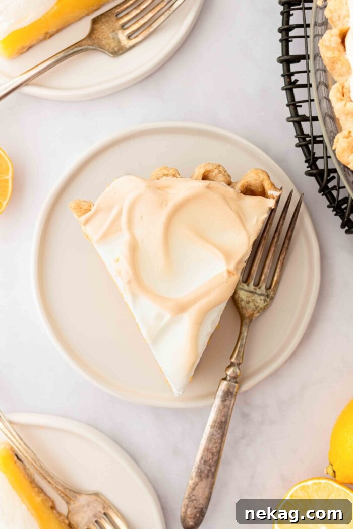 Classic Lemon Meringue Pie Recipe with Video Tutorial 14 Top view of a slice of lemon meringue pie on a plate.