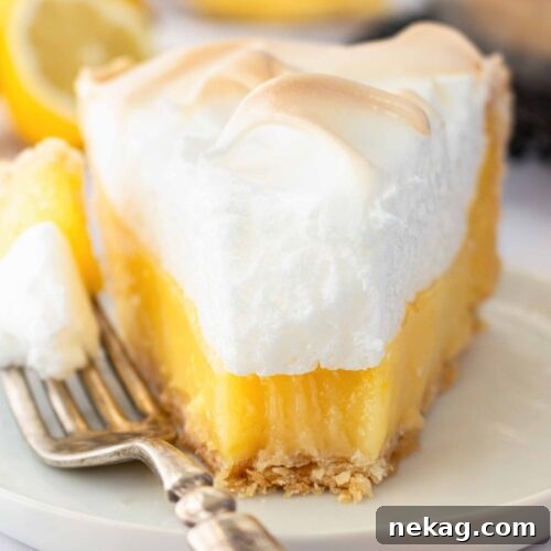 Classic Lemon Meringue Pie Recipe with Video Tutorial 15 Slice of lemon meringue pie on a plate with a forkful taken out.