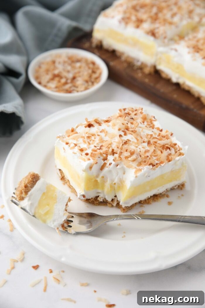 Slice of coconut delight on a plate with a forkful taken out.