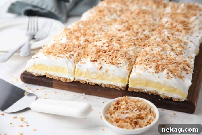 Coconut delight with layers of graham cracker crust, cream cheese, coconut pudding, whipped topping, and toasted coconut.