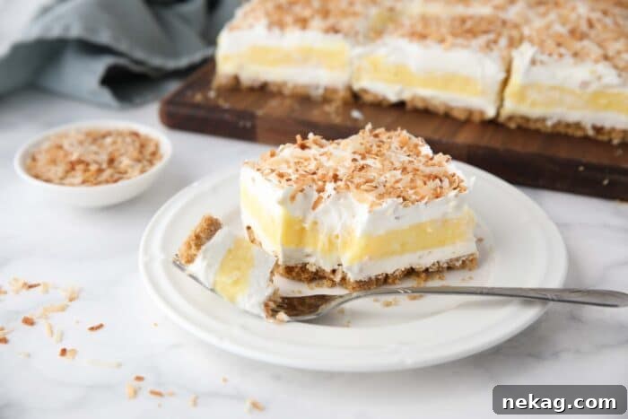 Slice of coconut lush on a plate with a forkful taken out.