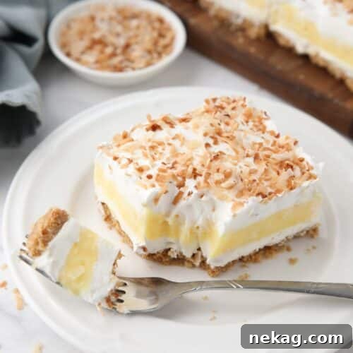 Slice of coconut delight on a plate with a forkful taken out.