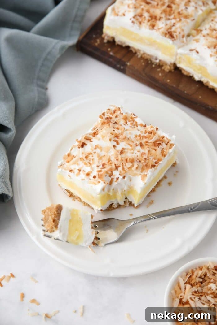 Slice of coconut cream bars on a plate with a forkful taken out.
