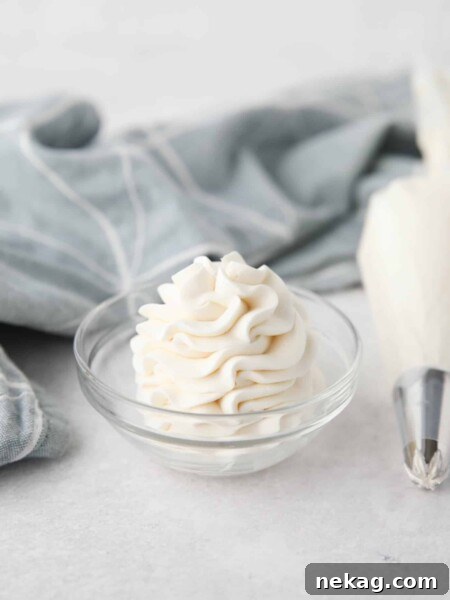 Whipped Cream Cheese Frosting piped high into a clear glass bowl.