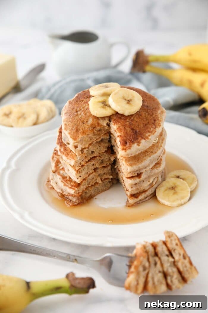 Fluffy 4-Ingredient Banana Pancakes Without Eggs 5 Stack of pancakes with bananas on top and a forkful taken out.