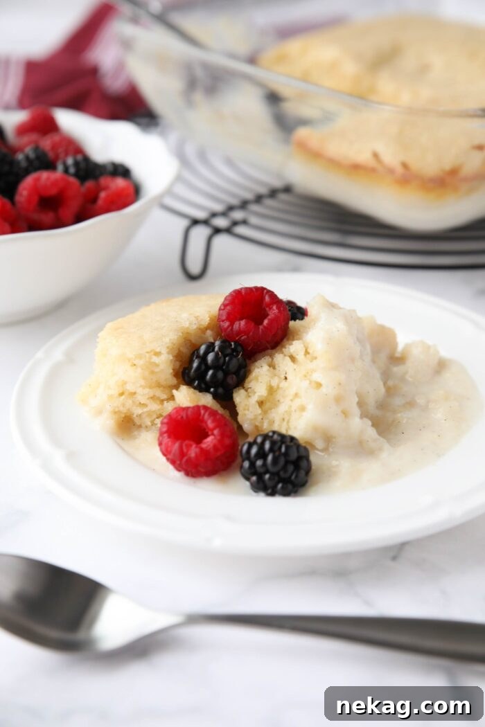 From scratch vanilla cake with vanilla pudding sauce on a plate with raspberries and blackberries.