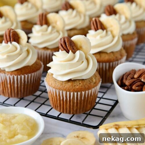 Southern-Style Hummingbird Cupcakes with Cream Cheese Frosting 13 Hummingbird Cupcakes on a wire rack with cream cheese frosting and a slice of banana and pecan on top.
