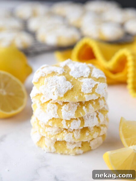 Stack of lemon crinkle cookies with powdered sugar on the outside.