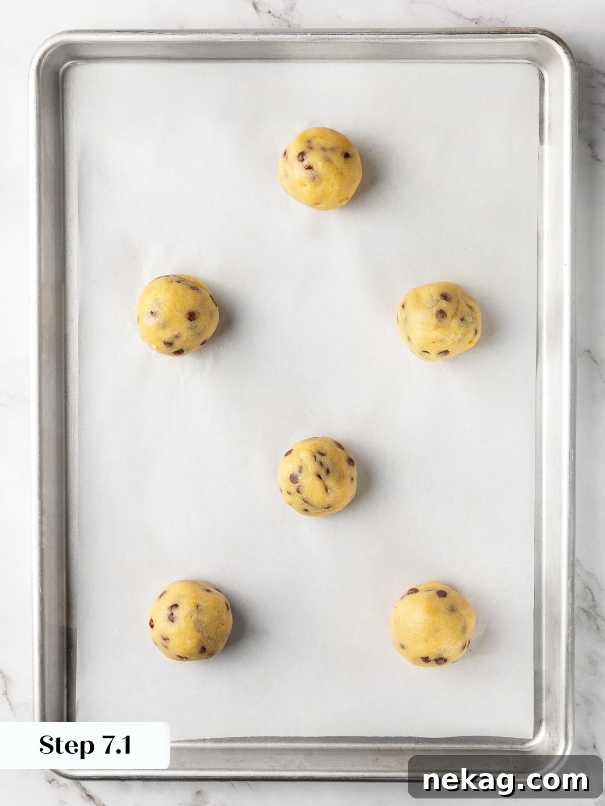 Large cookie dough balls spaced evenly on baking sheet ready for baking.