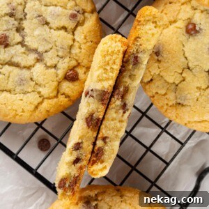 Chocolate chip cookie broken in half showing thick structure and soft, slightly gooey interior.