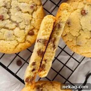 Chocolate chip cookie broken in half showing thick structure and soft, slightly gooey interior.