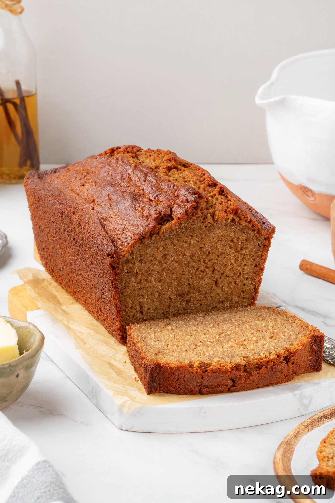 Moist Homemade Applesauce Bread Recipe 2 Tall caramelized loaf with a single freshly cut slice resting on parchment-lined wood and marble.