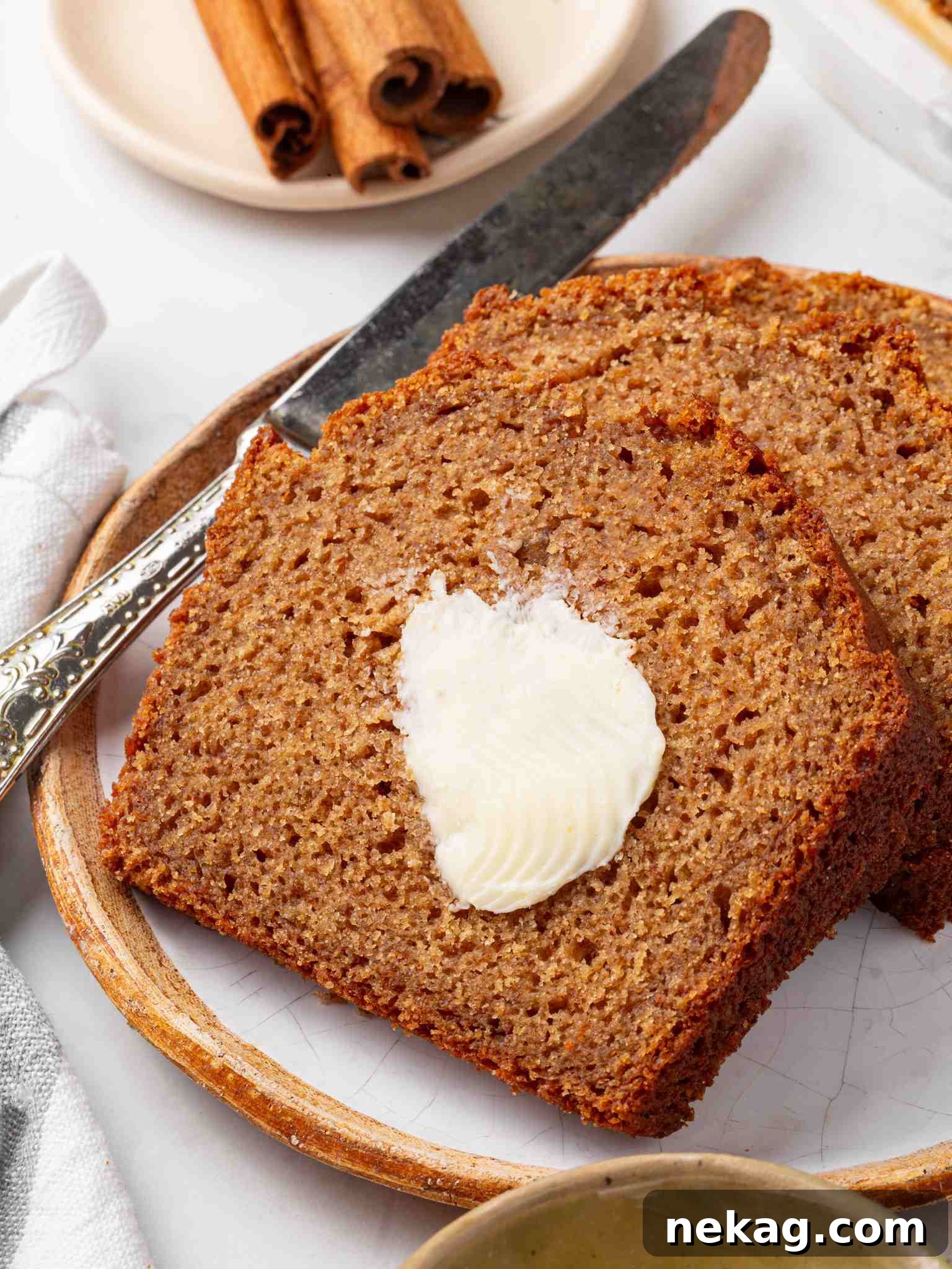 Moist Homemade Applesauce Bread Recipe 7 Detailed view of a buttered slice on a rustic wood-rimmed plate with an antique butter knife.