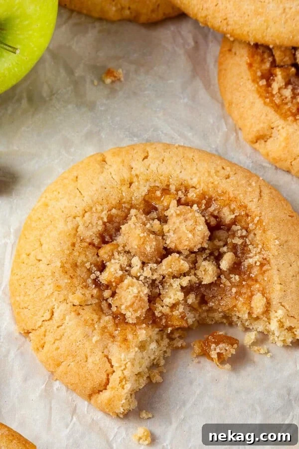 A single apple pie cookie with a bite revealing its chewy brown sugar dough and apple filling.