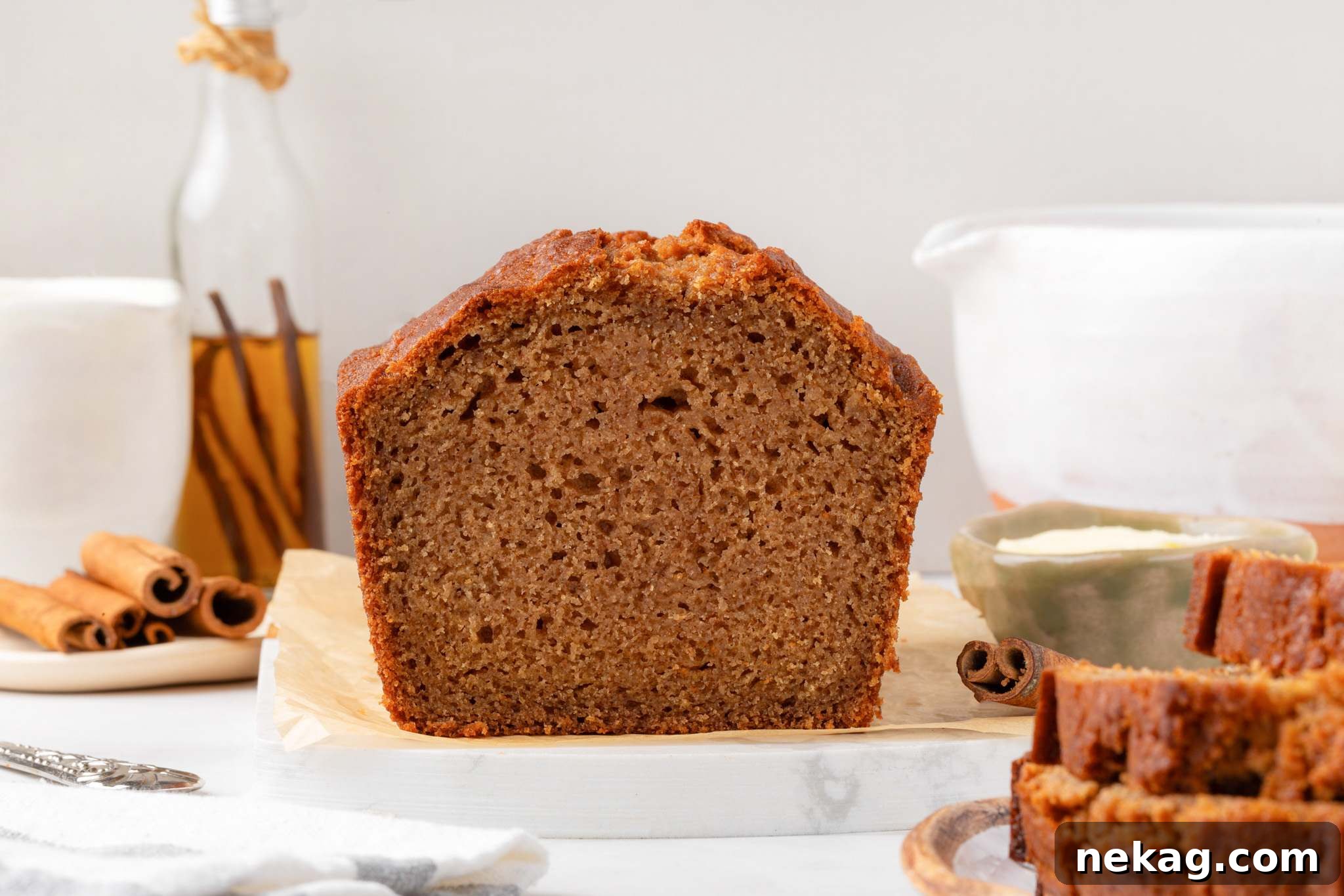 Moist Homemade Applesauce Bread Recipe 5 Cross-section of the loaf showing fine moist crumb framed by cinnamon sticks and a white pitcher.